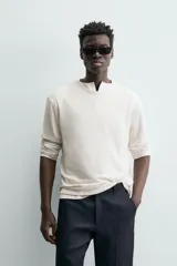 Camiseta de algodón color beige claro, de corte relajado (relaxed fit) con cuello redondo y manga corta. Presenta una textura sutil en el tejido.