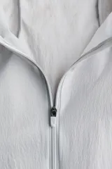 Campera deportiva liviana color gris, resistente al agua, con cuello elevado y cierre frontal. Cuenta con tecnología DryMove para absorber el sudor, mangas largas con puños elásticos y diseño plegable.