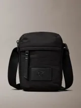 Cartera bandolera Calvin Klein color negro, confeccionada en nylon reciclado. Presenta correa ajustable, cierre superior con cremallera, bolsillo frontal y logo CK en relieve.
