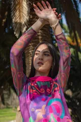 Vestido corto de terciopelo elastizado con estampado abstracto en tonos violeta, verde y celeste. Tiene cuello redondo tejido en color fucsia y mangas largas de tul.