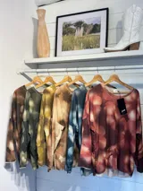 Remera de manga larga con diseño estampado de flores en tonos marrones y destellos de lurex. Presenta un corte holgado, cuello redondo y puños en color gris claro.