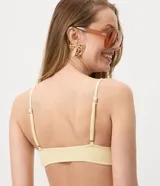 Top de bikini bandeau color amarillo claro, confeccionado en microfibra texturada con tirantes finos regulables adornados con cuentas y caracolas.