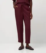 Pantalón de vestir femenino color marrón oscuro, de corte fluido y tiro medio/alto, con cintura elástica ajustable mediante cordón. Presenta bolsillos laterales y cierre frontal.