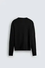 Jersey de manga larga, cuello redondo y calce relajado, color negro con efecto lavado y textura tejida.