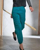 Pantalón babucha color beige de algodón, con corte a la cintura y piernas levemente amplias. Presenta textura de tablitas centrales y elásticos con broches inferiores que ajustan las piernas al tobillo.