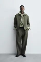 Sobrecamisa de corte boxy fit confeccionada en tejido compacto color beige, con cuello solapa, cierre frontal de botones y bolsillos laterales en costura.