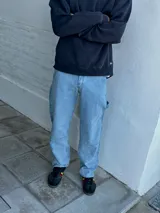 Jean azul claro de corte amplio, estilo carpintero, con pespuntes en contraste y cierre en el tobillo.