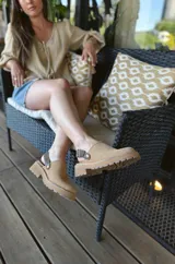 Zuecos de cuero color beige, con suela track y tira trasera ajustable.