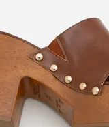 Sandalias de plataforma color marrón con tiras de cuero sintético y tachuelas doradas.