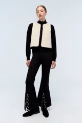 Chaleco negro de pana con bordes color beige y lazos de ajuste frontales.