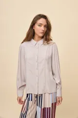 Camisa de manga larga color celeste, con cuello clásico y botonadura frontal. Presenta un calce relajado, con mangas amplias y puños anchos.