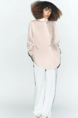 Camisa de corte oversize con estampado de rayas verticales, cuello subido y cierre frontal con botones. Presenta mangas largas con puños y un diseño cruzado en la parte delantera.
