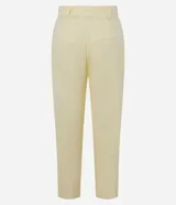 Pantalón zanahoria de tiro alto color amarillo pálido, confeccionado en viscolino con 15% de lino, con trabillas en la cintura, solapas con botón abajo de la cintura, pliegues y cierre tradicional.