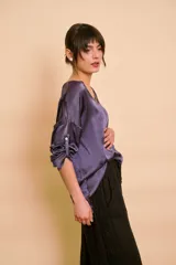 Blusa holgada de satén color beige, con escote en V y mangas largas con trabilla para sujetar remangadas.