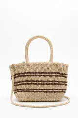 Bolso tipo shopper tejido en tono beige con detalles de rayas horizontales marrones, doble asa rígida de mano y correa larga ajustable y desmontable.