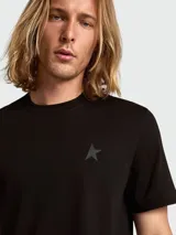 Remera negra de manga corta con cuello redondo y un pequeño logo de estrella en tono negro mate en el pecho.