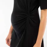 Vestido midi negro de manga corta, con cuello redondo y detalle de torsión en la cintura que genera un drapeado lateral. Presenta un tajo lateral en el ruedo.