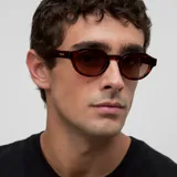 Lentes de sol con montura geométrica de acetato color carey (tortoise) y cristales marrones polarizados. El diseño combina una parte superior plana con una parte inferior redondeada.