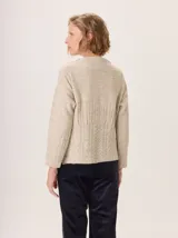 Buzo de lana color beige con cuello chimenea, mangas largas y diseño de tejido trenzado en la parte inferior y puños.