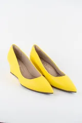 Zapatos cerrados de ecocuero color amarillo, con taco corrido y punta fina. Cuentan con forro textil interno.
