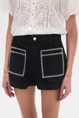 Short de jean color azul oscuro, de calce alto y ajustado al cuerpo. Presenta dos bolsillos frontales cuadrados con bordado decorativo en color blanco.