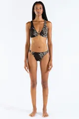 Bombacha de bikini con estampado animal print tipo cebra en tonos negro y beige, confeccionada en jacquard. Cuenta con un aro metálico decorativo en el lateral de la cadera.