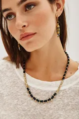 Collar corto con cuentas de metal dorado y cuentas de vidrio azul oscuro, con detalles de pequeñas borlas doradas en la parte frontal.