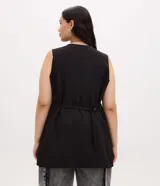 Chaleco sastre de corte alargado, color negro, con escote en V profundo y diseño sin mangas. Presenta un estilo minimalista con bolsillos laterales simulados y ajuste entallado en la espalda.