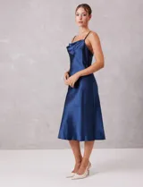 Vestido midi de satén color azul marino, con escote drapeado y breteles finos regulables. Presenta una silueta fluida con caída suave.