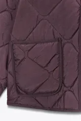 Chaqueta acolchada de cuello redondo y manga larga, con cierre frontal de botones y dos bolsillos delanteros de plastrón. Presenta un diseño de costuras en forma de rombos.