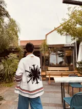 Cardigan tejido artesanalmente en lana color crudo, con diseño de copo de nieve en la espalda y bordados a mano.