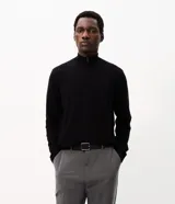 Suéter negro de punto fino para hombre, con cuello alto y medio cierre frontal con cremallera, mangas largas y diseño de corte recto.