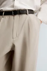 Pantalón de corte relajado confeccionado en tejido con mezcla de lyocell. Presenta cintura con trabillas, cierre frontal con cremallera y botón, pliegues en el delantero, bolsillos laterales y bolsillos traseros de vivo.