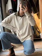 Sweater de punto color beige con cuello en V, diseño oversize y costura central frontal visible.