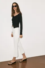 Pantalón mini flare de tiro medio, color negro, con diseño evasé y raya central marcada. Cuenta con cierre lateral mediante cremallera oculta.