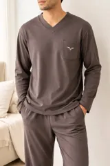 Pijama de dos piezas compuesto por una remera de manga larga con cuello en V y bolsillo frontal con logo bordado, y un pantalón largo a juego. Confeccionado en tejido suave de color gris oscuro.