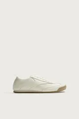 Zapatilla de estilo retro con cordones, confeccionada en una combinación de piezas de cuero sintético en color blanco, con suela dentada de goma en tono caramelo.