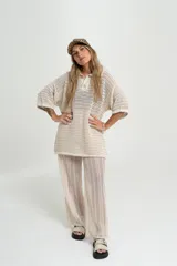 Pantalón de tejido calado color crudo, con cintura elástica y corte palazzo.