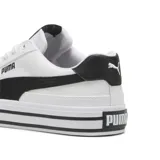 Championes Puma modelo Court Classic Vulc, de diseño urbano con capellada de lona blanca y detalles en cuero sintético negro. Presenta suela de plataforma con líneas decorativas horizontales y cierre de cordones.
