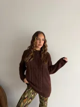 Buzo de punto en color beige, con diseño de trenzas verticales en el frente, cuello redondo y mangas largas con puños acanalados.