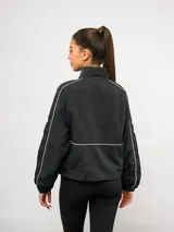 Campera deportiva Umbro de nylon color negro, con cuello alto, cierre frontal y detalles de líneas blancas en contraste. Presenta bolsillos laterales y puños elásticos.