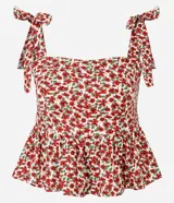 Blusa de viscosa y lino con estampado floral en tonos rojos y blancos. Presenta escote cuadrado, cuerpo ajustado con fruncido en la cintura y bajo con volado (peplum). Los breteles son anchos y se atan con lazos en los hombros.