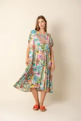 Vestido largo estampado con motivos tropicales en tonos verdes, naranjas, azules y rosados, con cuello redondo y mangas cortas.