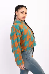 Campera corta de polar color beige con estampado de estrellas negras, cuello alto y cierre frontal.