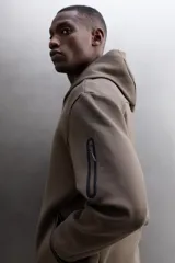 Campera canguro de Zara Athleticz, modelo relaxed fit, confeccionada en tejido técnico compacto elástico con mezcla de algodón en color azul marino. Cuenta con cuello subido con capucha, manga larga con bolsillo lateral con cierre, bolsillos frontales con cierre y acabado termofijado, cierre frontal de doble dirección y logo estampado en el bajo.