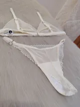 Conjunto de lencería compuesto por un corpiño triangular y una bombacha tipo tanga, confeccionados en encaje con diseño de ondas y terminaciones delicadas.