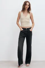 Top de punto color beige, con cuello halter y escote redondo pronunciado, de diseño ajustado al cuerpo.
