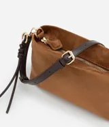 Bolso transversal Satinato de tamaño mediano, confeccionado en material sintético símil gamuza color marrón, con correa ajustable oscura, herrajes dorados y tiras decorativas colgantes con nudo.