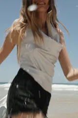 Short de jean negro desgastado, tiro alto, con roturas pronunciadas y terminación deshilachada en el bajo. Presenta cinco bolsillos y cierre frontal con botón metálico.