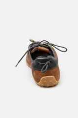 Championes de gamuza color marrón con detalles en cuero liso del mismo tono. Presentan cordones bicolores en naranja y negro, suela de goma plana y un detalle en color rojo en la parte trasera del talón.